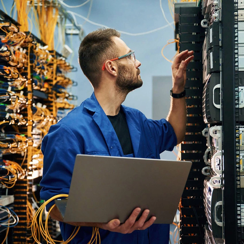 man is working with internet equipment and wires in server room